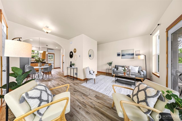 living room featuring arched walkways, wood finished floors, and baseboards