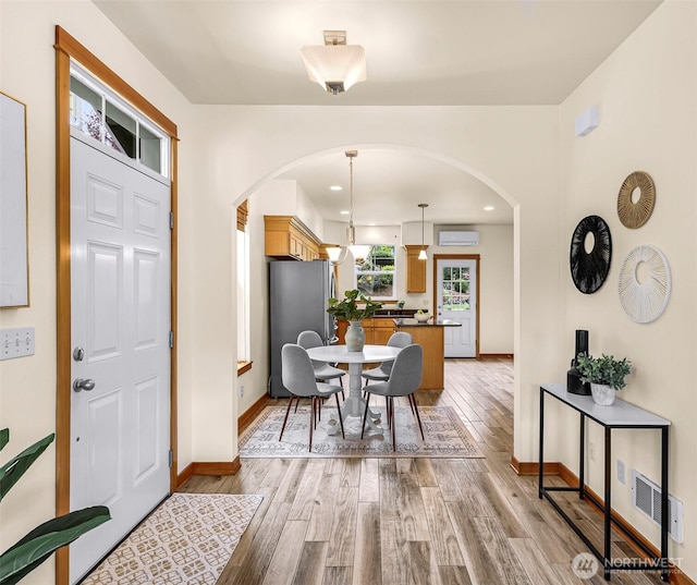 dining area with arched walkways, light wood-type flooring, baseboards, and recessed lighting