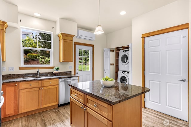 kitchen featuring dishwasher, stacked washer / dryer, a sink, an AC wall unit, and light wood finished floors