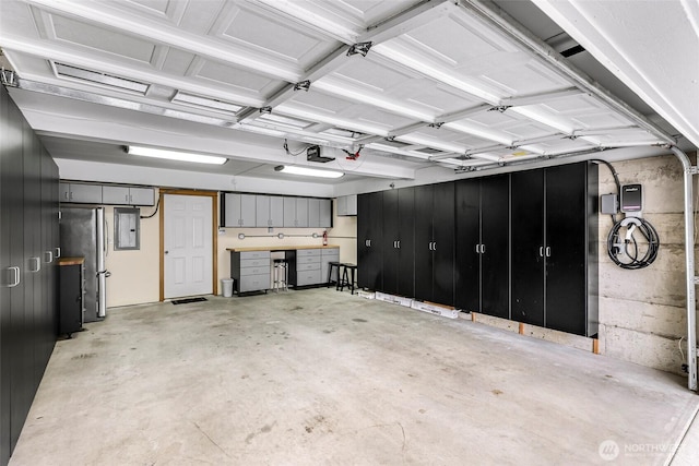 garage featuring a garage door opener, freestanding refrigerator, and electric panel