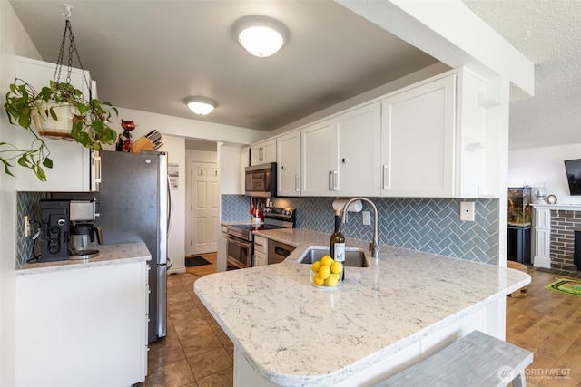20145 Vikings Crest Loop NE Unit 3-105, Poulsbo, WA 98370 - kitchen featuring white cabinetry, a sink, stainless steel appliances, a peninsula, and backsplash