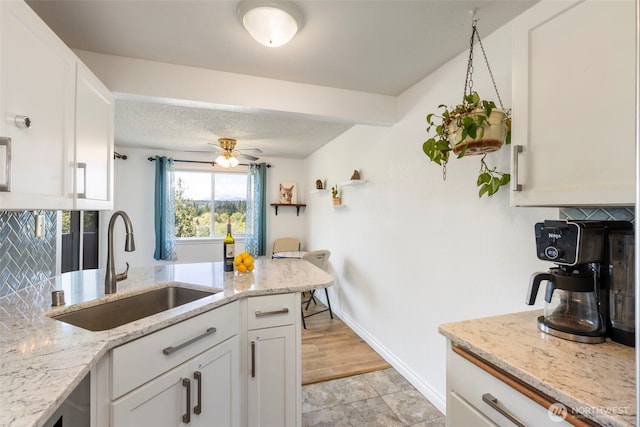 20145 Vikings Crest Loop NE Unit 3-105, Poulsbo, WA 98370 - kitchen with light stone counters, white cabinetry, baseboards, and a sink