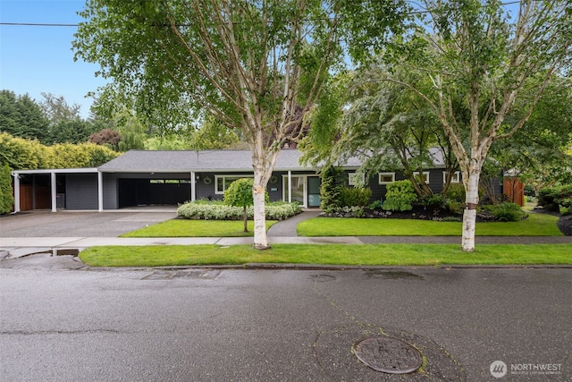 ranch-style house with asphalt driveway, an attached carport, a front lawn, and a garage