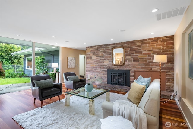 living area featuring wood finished floors, a stone fireplace, and baseboards