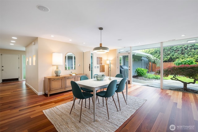 dining room with light wood finished floors, baseboards, a wall of windows, and recessed lighting