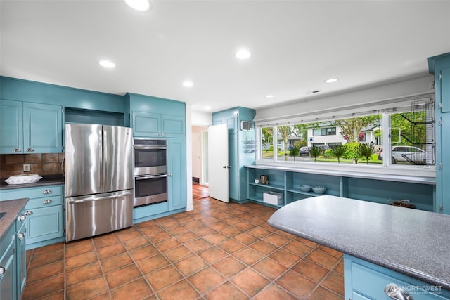 kitchen with appliances with stainless steel finishes, backsplash, recessed lighting, blue cabinetry, and dark countertops
