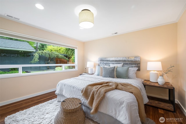 bedroom featuring baseboards, wood finished floors, and ornamental molding