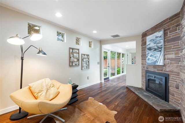 living area featuring wood finished floors, a large fireplace, crown molding, baseboards, and recessed lighting