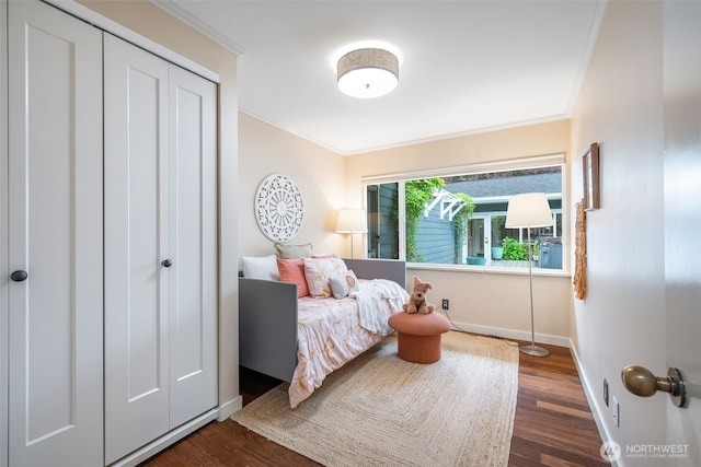 bedroom with crown molding, wood finished floors, baseboards, and a closet