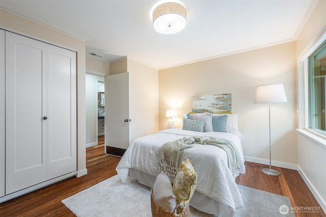 bedroom with wood finished floors, crown molding, and baseboards