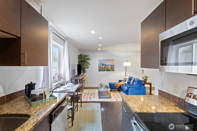 kitchen featuring light stone countertops, stainless steel appliances, recessed lighting, baseboards, and dark wood-type flooring