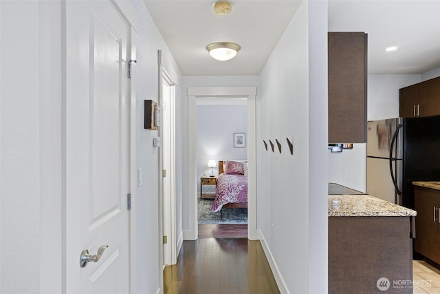 corridor with baseboards and wood finished floors