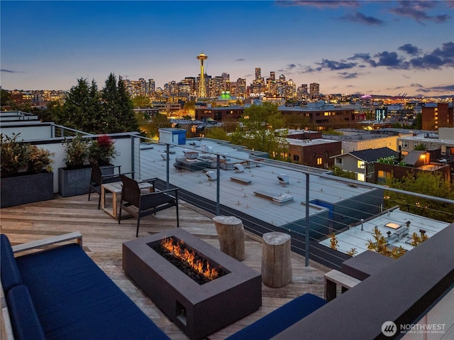 balcony at dusk with a view of city and an outdoor fire pit