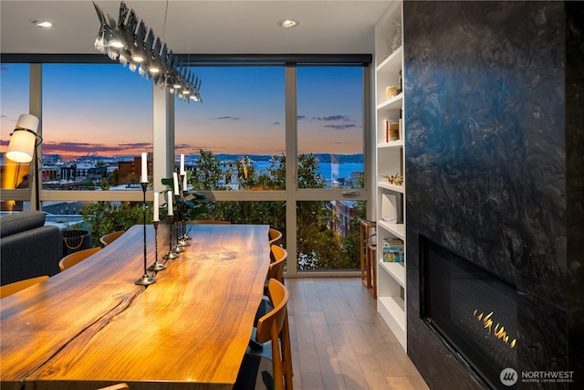 dining space with expansive windows, recessed lighting, wood finished floors, and a large fireplace