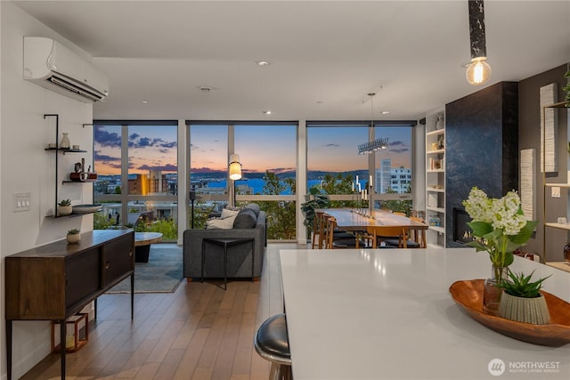 dining room with wood-type flooring, a wall of windows, and a wall unit AC