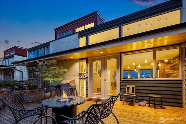 rear view of property featuring french doors, a fire pit, and a deck