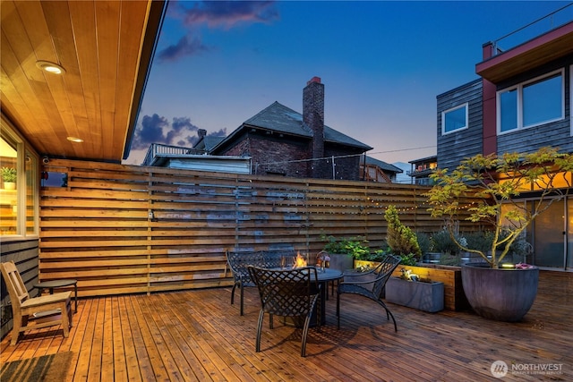 deck at dusk featuring fence and outdoor dining area