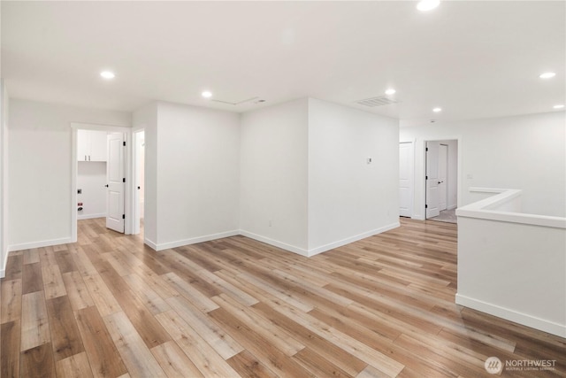 spare room featuring light wood finished floors, baseboards, visible vents, and recessed lighting