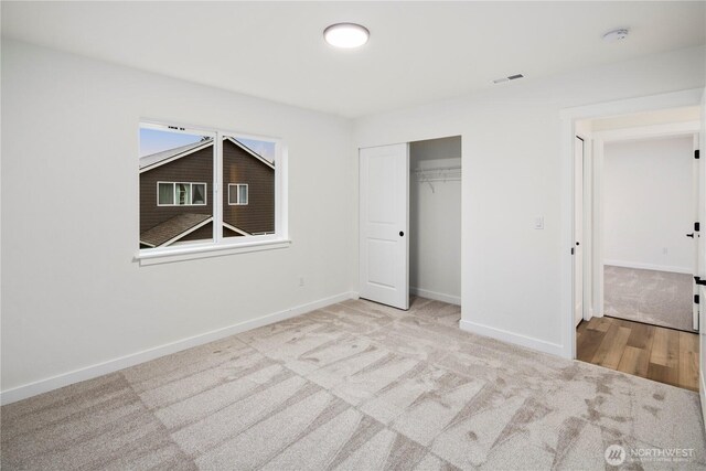 unfurnished bedroom with carpet floors, a closet, visible vents, and baseboards