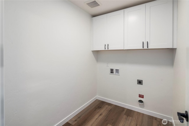clothes washing area with hookup for an electric dryer, dark wood finished floors, baseboards, visible vents, and cabinet space