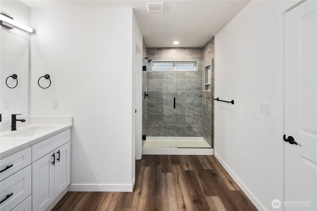 bathroom with baseboards, wood finished floors, visible vents, and vanity