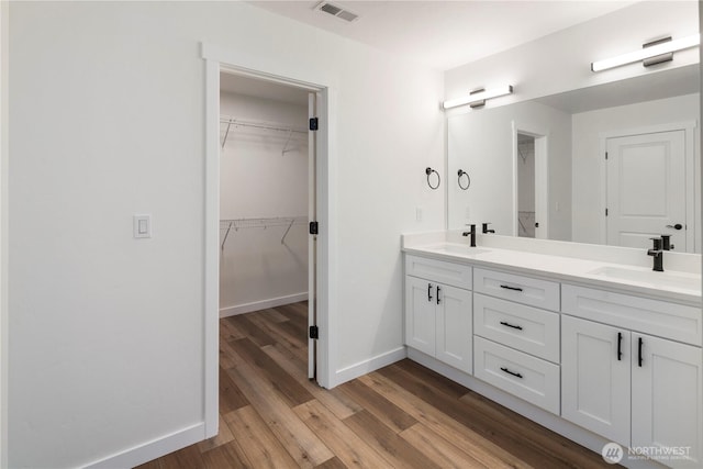 full bathroom with double vanity, visible vents, wood finished floors, and a sink