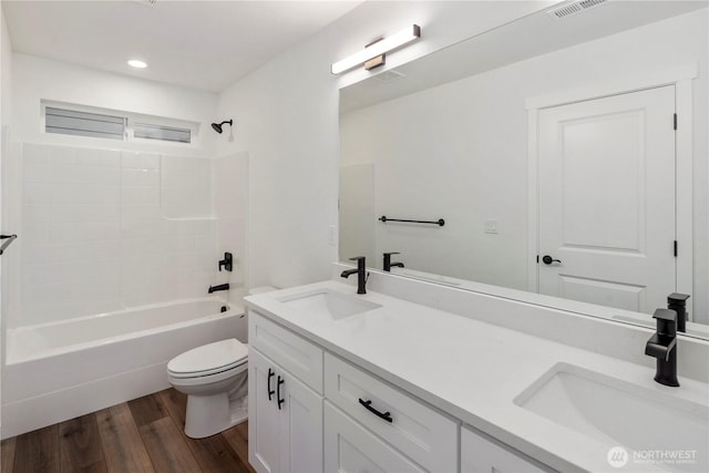 full bath with toilet, wood finished floors, a sink, and shower / tub combination