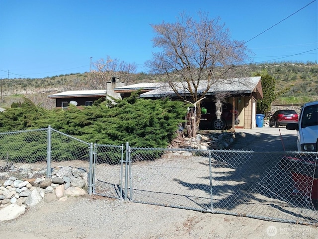 view of property hidden behind natural elements featuring fence, a gate, and a chimney