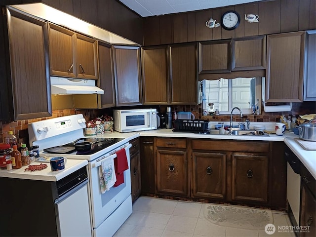 kitchen featuring under cabinet range hood, white appliances, and light countertops