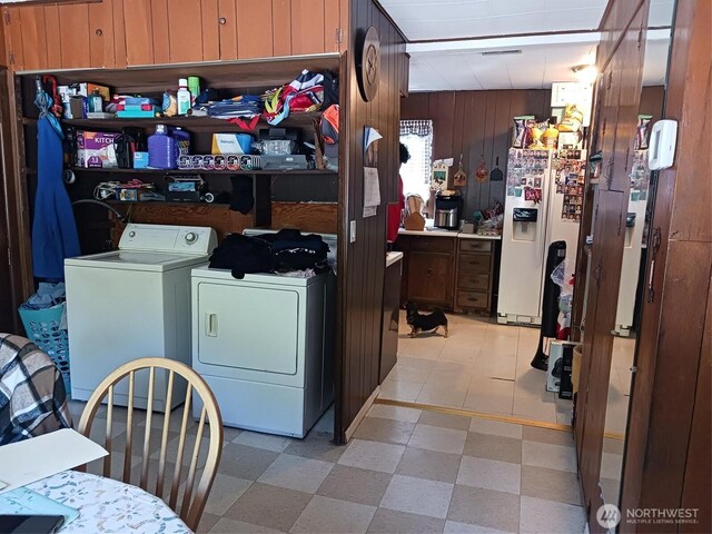 washroom featuring wooden walls, light floors, laundry area, and washing machine and dryer