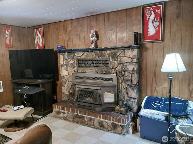 living room featuring wooden walls, tile patterned floors, and a wood stove