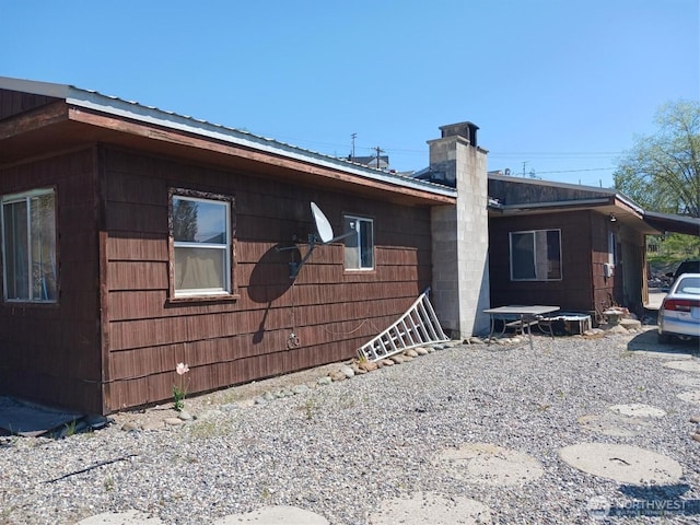 view of home's exterior featuring a chimney and metal roof