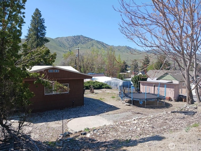 view of yard featuring an outbuilding, a mountain view, and a trampoline