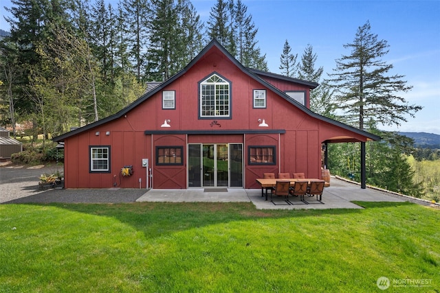 rear view of property featuring a lawn, a patio, and board and batten siding