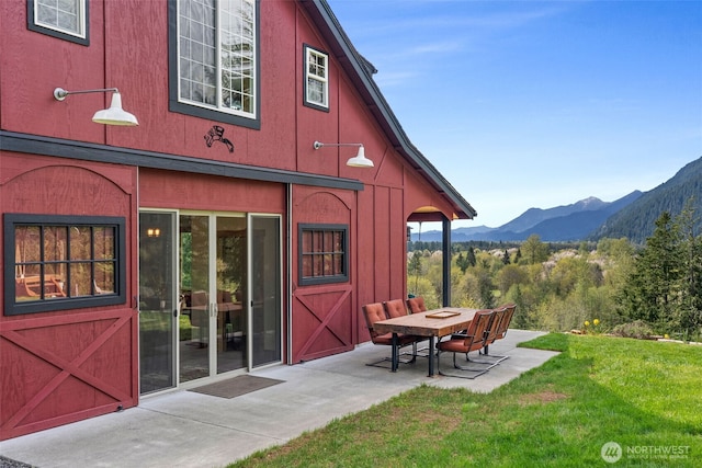rear view of house featuring a mountain view, a yard, and a patio area