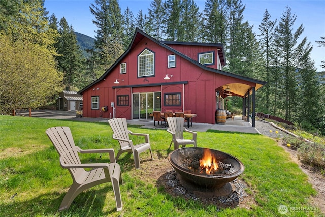 back of property featuring a patio, board and batten siding, a fire pit, and a lawn