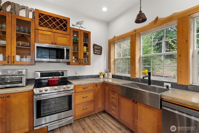 kitchen featuring brown cabinets, appliances with stainless steel finishes, a sink, light wood finished floors, and a toaster