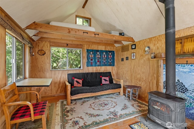 sitting room featuring vaulted ceiling, a wood stove, and a healthy amount of sunlight