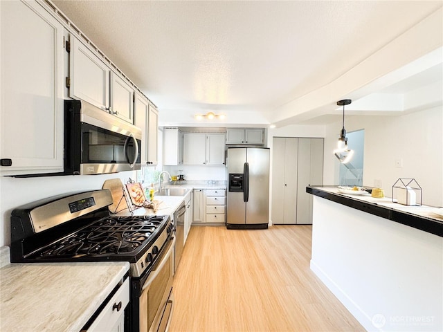 27526 26th Ave S, Federal Way, WA 98003 - kitchen featuring appliances with stainless steel finishes, light wood-style floors, pendant lighting, a sink, and light countertops