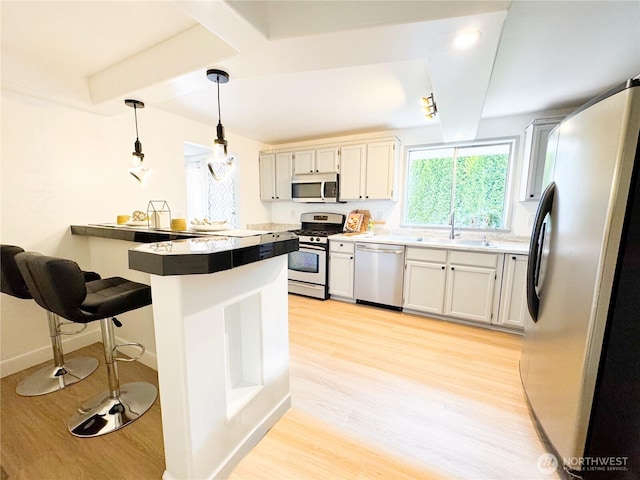 27526 26th Ave S, Federal Way, WA 98003 - kitchen featuring appliances with stainless steel finishes, light wood-style flooring, a breakfast bar, a peninsula, and a sink