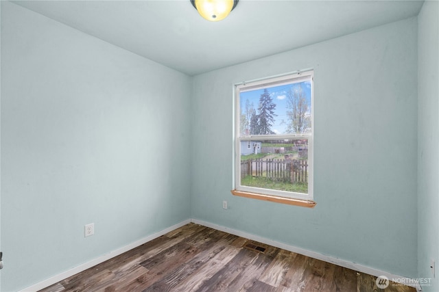 empty room featuring baseboards and dark wood-type flooring