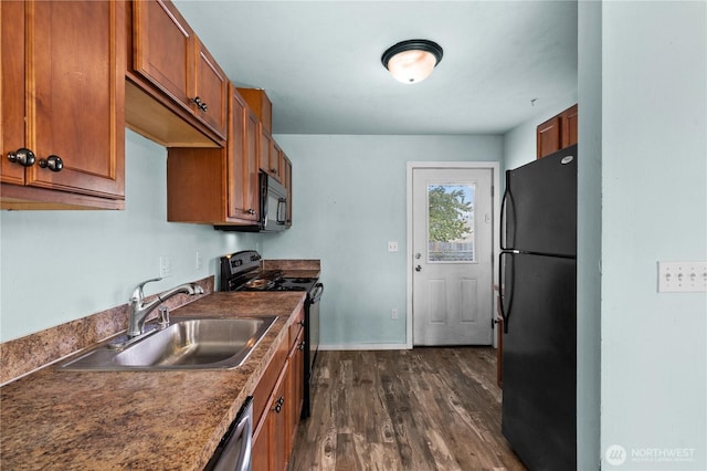 kitchen with a sink, dark countertops, brown cabinetry, dark wood-type flooring, and black appliances