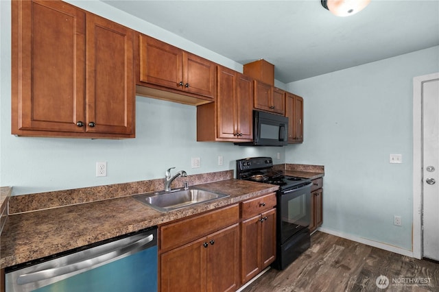 kitchen featuring dark countertops, a sink, black appliances, brown cabinets, and dark wood-style flooring