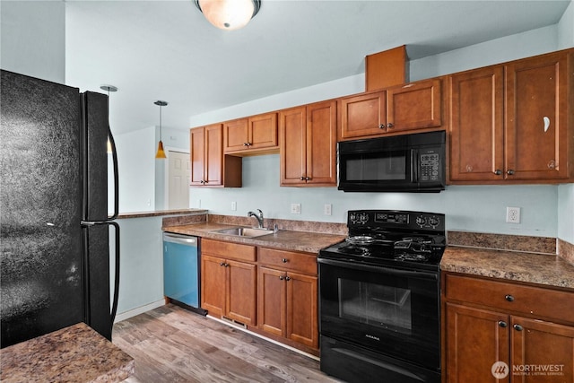 kitchen with light wood-style flooring, brown cabinetry, a sink, and black appliances