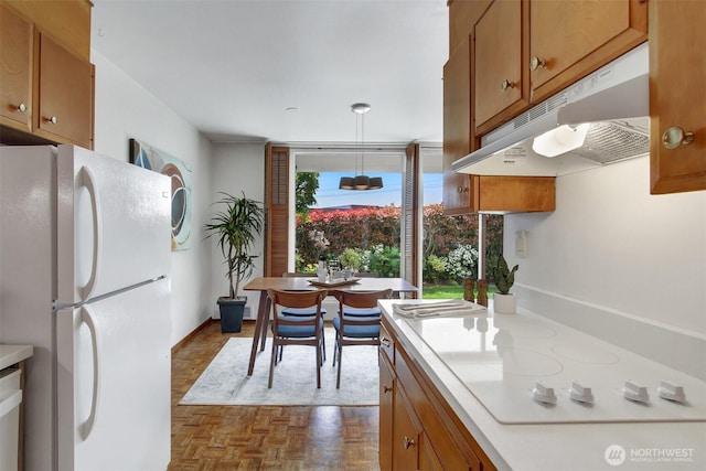 kitchen with brown cabinets, white appliances, light countertops, baseboards, and under cabinet range hood