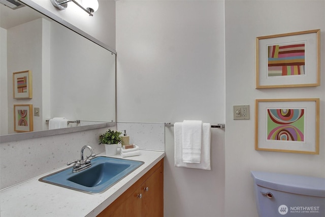half bath featuring toilet, visible vents, and vanity
