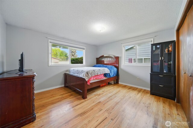 bedroom featuring a textured ceiling, baseboards, and light wood finished floors