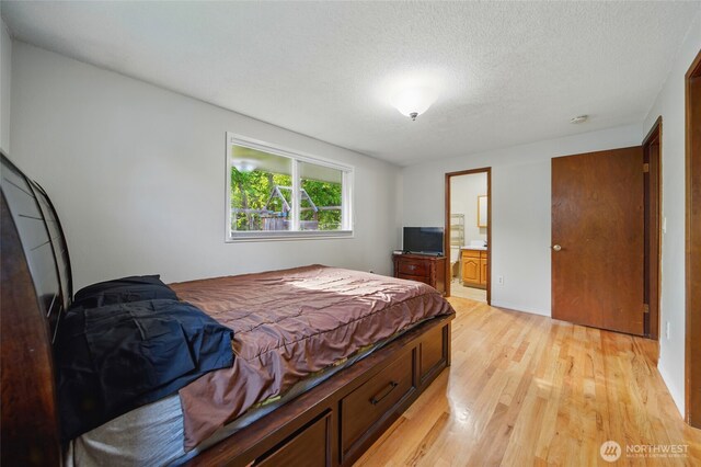 bedroom featuring connected bathroom, a textured ceiling, and light wood-type flooring