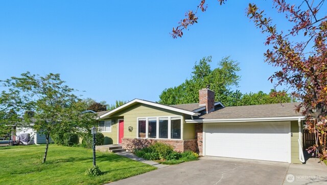 single story home with a chimney, a front yard, a garage, brick siding, and concrete driveway