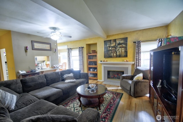 living room with ceiling fan, wood finished floors, and a tiled fireplace